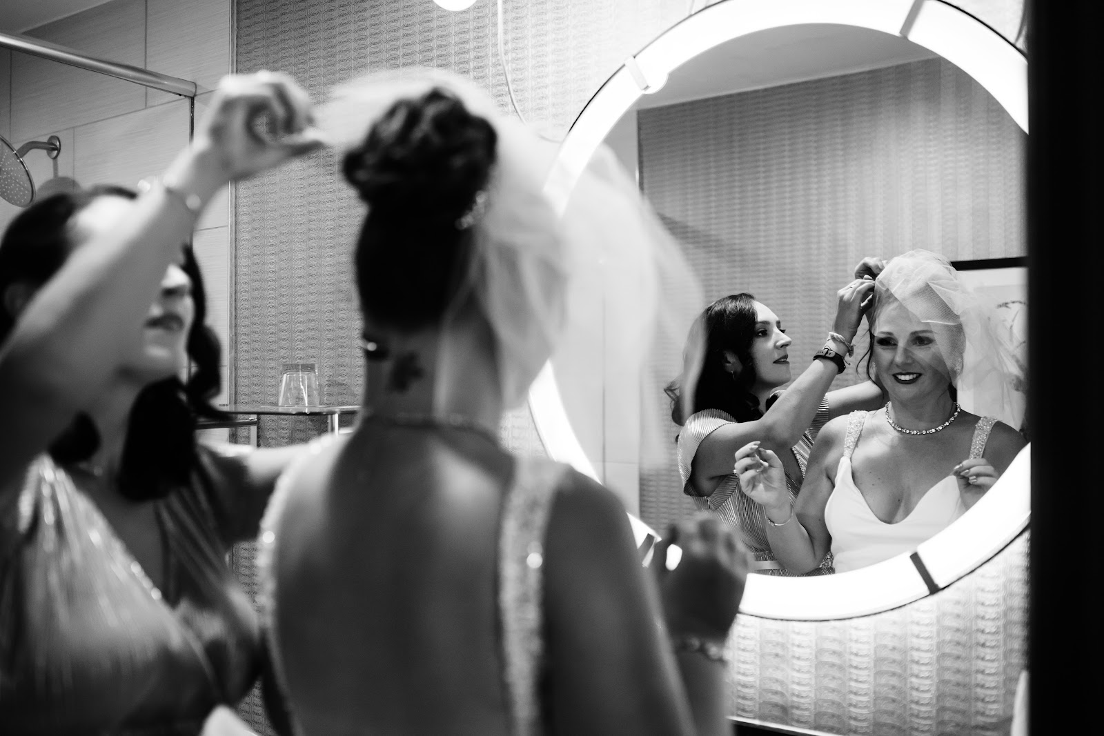 person helping bride to finish wedding beauty plans by putting on her veil